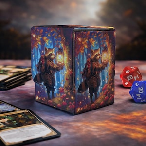 May include: A rectangular deck box featuring a printed illustration of a raccoon wearing a backpack and holding a glowing lantern in a forest setting with autumn leaves and red mushrooms. The box has a magnetic flap closure and textured surface.