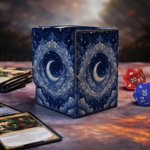 May include: A rectangular deck box featuring a dark blue night sky pattern with a central crescent moon surrounded by ornate, cloud-like circular frames and scattered stars. The box has a hinged lid and a textured finish, displayed with gaming dice.