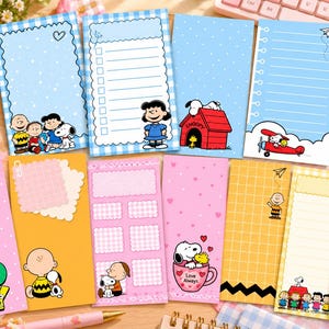 Może przedstawiać: Kolekcja prostokątnych papierowych notatników z postaciami z Fistaszków, w tym Snoopy, Charlie Brown i Lucy. Wzory obejmują kropki, kratki i paski w kolorach niebieskim, różowym, żółtym i zielonym z nadrukowanym tekstem.