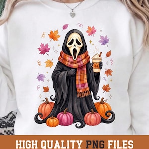 May include: A white sweatshirt featuring a graphic of a black-robed figure with a white mask, wearing a plaid scarf, holding a coffee cup with a pumpkin design, surrounded by colorful autumn leaves and orange and pink pumpkins.