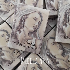 Może przedstawiać: Stos małych pudełek z wizerunkiem twarzy kobiety na przodzie. Pudełka są oznaczone "Sepia Middia Lenormand" i "Middia Arts".