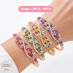 May include: Gold-toned floral bracelets with colorful enamel flowers and sparkling accents. The bracelets are adorned with pink, green, yellow, and purple flowers. The image includes the text "Single / 2PCS / 4PCS".