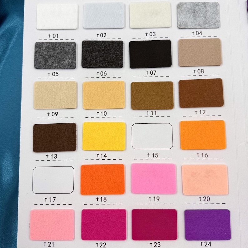 May include: A colour swatch chart displaying 24 rectangular felt samples in a range of hues. The samples are arranged in rows and columns, each colour labelled with a number from 01 to 24. Colours include white, grey, black, brown, yellow, orange, pink, and purple.