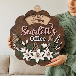 May include: A dark brown wooden sign with a scalloped edge featuring the text DO NOT DISTURB, Scarlett's, and Office. The sign is decorated with layered white lily flowers, green leaves, and three butterflies in a light wood finish.