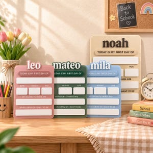 May include: Four rectangular milestone boards in pink, dark green, light blue, and beige, each featuring raised lettering with names like Leo, Mateo, Mila, and Noah. The boards include blank spaces for date, height, age, and personal interests.
