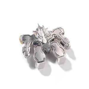 May include: A silver-toned pendant with a geometric design, featuring a central star-like element and multiple stylized shapes. The pendant is encrusted with small, sparkling stones and accented with gold and blue details.