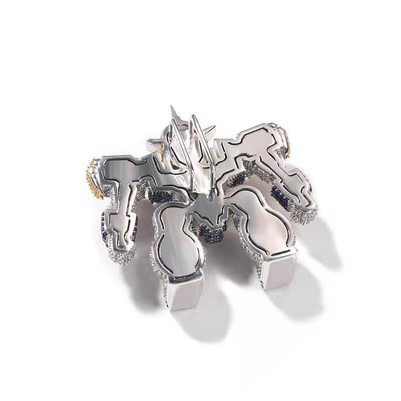 May include: A silver-toned pendant with a geometric design, featuring a central star-like element and multiple stylized shapes. The pendant is encrusted with small, sparkling stones and accented with gold and blue details.