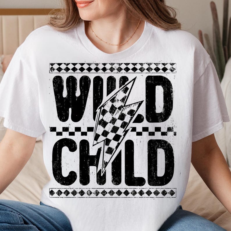 Puede incluir: Camiseta blanca con dise&ntilde;o gr&aacute;fico negro. El dise&ntilde;o presenta las palabras "WILD CHILD" con un rayo de bandera a cuadros. La camiseta tiene cuello redondo y mangas cortas.