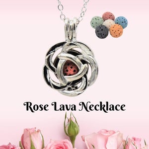 Puede incluir: Un collar plateado con un colgante en forma de rosa que contiene una piedra de lava roja. El collar cuelga de una cadena plateada. También se muestran varias cuentas de piedra de lava de colores. El texto dice "Rose Lava Necklace".