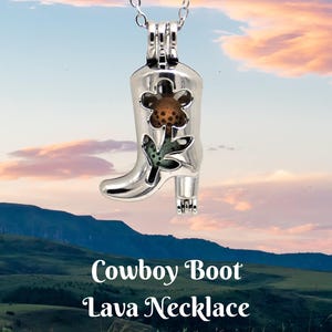 Puede incluir: Un collar con colgante de bota de vaquero plateada con un diseño floral. La bota tiene una flor recortada con centro marrón y hojas verdes. El texto "Cowboy Boot Lava Necklace" está en la parte inferior de la imagen.