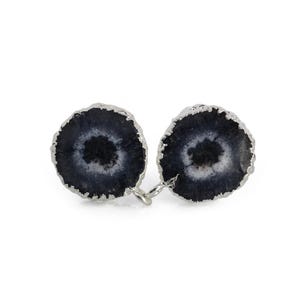 May include: A pair of round, dark blue and white stone earrings with a silver-colored metal trim. The earrings have a circular pattern with a dark center and a lighter outer ring. The earrings are connected by a small silver-colored metal loop.