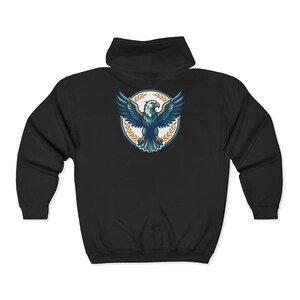 May include: A black zip-up hoodie featuring a graphic on the back. The design displays a stylized eagle with spread wings centered within a circular emblem, surrounded by a gold-colored laurel wreath pattern against a white background.