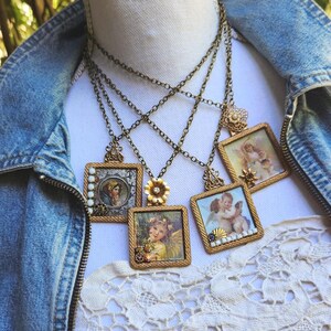 May include: A collection of vintage-style necklaces with square pendants featuring angel and portrait illustrations. The pendants are framed in ornate gold-toned metal and hang from delicate chains. Some pendants have floral or bead accents.