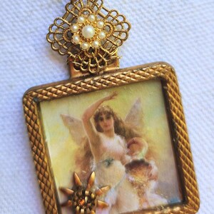 May include: A vintage gold-toned pendant necklace. The pendant features a rectangular frame with a detailed image of a woman with wings. The frame is adorned with a star and a decorative top with pearls. The chain is also gold-toned.