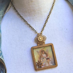 May include: A vintage-style necklace with a gold-toned chain and pendant. The pendant features a rectangular frame with a detailed image of a fairy. The necklace has a delicate, ornate design, perfect for adding a touch of whimsy to any outfit.