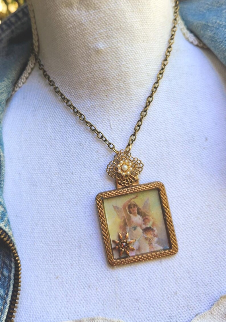 May include: A vintage-style necklace with a gold-toned chain and pendant. The pendant features a rectangular frame with a detailed image of a fairy. The necklace has a delicate, ornate design, perfect for adding a touch of whimsy to any outfit.
