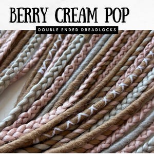 May include: Close-up of double-ended dreadlocks in shades of brown, pink, and gray. The dreadlocks are braided and have white accents. The text "BERRY CREAM POP" and "DOUBLE ENDED DREADLOCKS" is at the top.