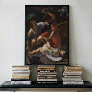 May include: A rectangular framed print of a classical painting featuring figures in red and white robes, positioned above a black tufted leather bench with a metal frame. Three stacks of books are arranged on the bench beneath the artwork.