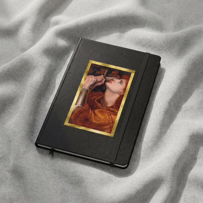 May include: A black hardcover notebook featuring a rectangular print of a painting on the front cover. The artwork depicts a person with reddish hair wearing an orange garment, holding a metallic object near their face, framed in gold.