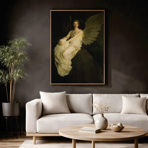 May include: A framed wall art print depicting a winged figure in a flowing white gown seated on a dark stone ledge. The figure has a somber expression and large feathered wings. The artwork features a dark, moody color palette with deep shadows.