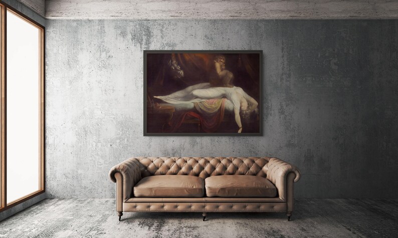 May include: A framed oil painting depicting a reclining figure draped in white fabric, positioned above a tufted tan leather sofa. The artwork features dark, moody tones with a central illuminated subject, hanging on a textured grey concrete wall.