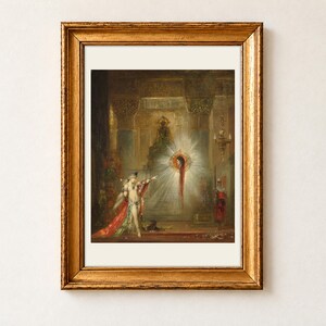 The Apparition by Gustave Moreau, 1876, as a framed print with a cream border in an antique gold frame on a cream wall. Salome points towards the glowing, haloed head of John the Baptist as it appears in the air before her inside a richly decorated palace.