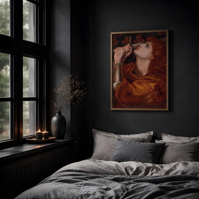 May include: A framed rectangular wall art print featuring a painting of a person with long red hair, wearing a golden garment and holding a sword near their face. The artwork is displayed on a dark gray wall above a bed with gray bedding.