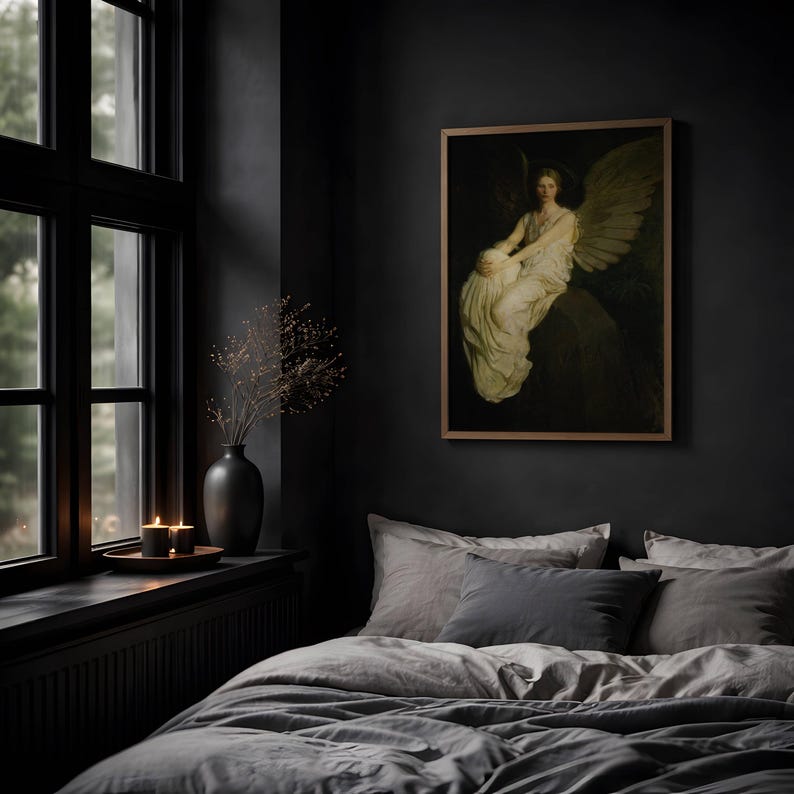 May include: A framed wall art print depicting a winged figure in a white robe sitting on a dark stone, displayed in a room with a dark gray wall, a black vase with dried branches, two lit candles, and a bed with gray bedding.