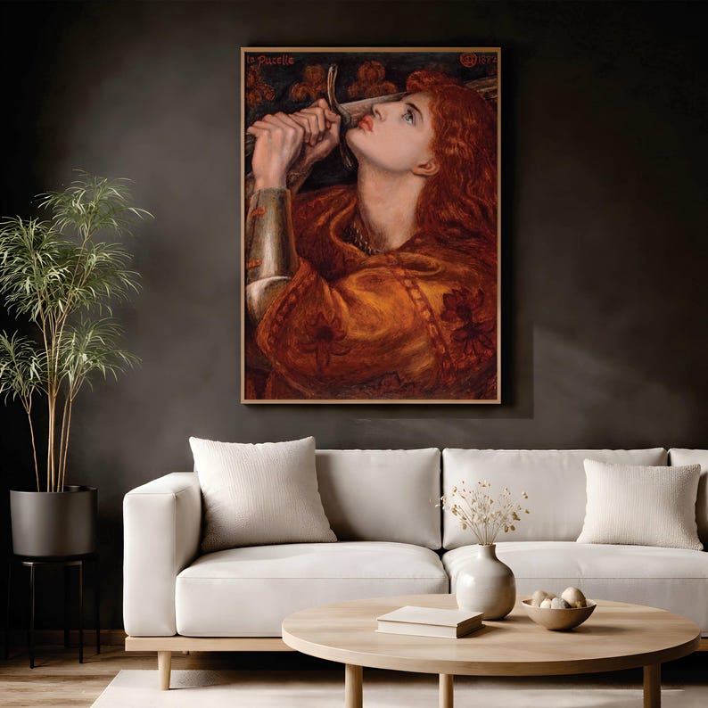 May include: A framed oil painting titled La Pucelle depicting a person with long red hair wearing armor and holding a sword near their face. The artwork features warm orange and brown tones with floral patterns on the garment.
