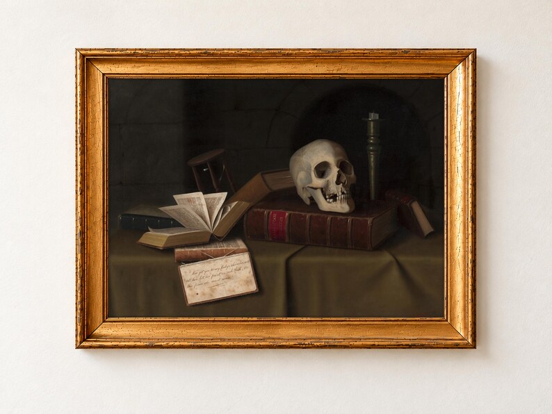Memento Mori, To This Favour by William Michael Harnett, 1879, as a framed print in an antique gold frame on a cream wall. A human skull rests on a leather-bound book beside an hourglass, a candlestick, an open book and a handwritten note quoting Hamlet.
