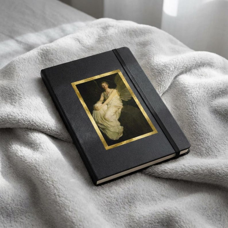 May include: A black hardcover notebook featuring a rectangular gold-framed print of a classical painting depicting a seated figure in a white gown with wings. The notebook includes a vertical black elastic band closure attached to the front cover.