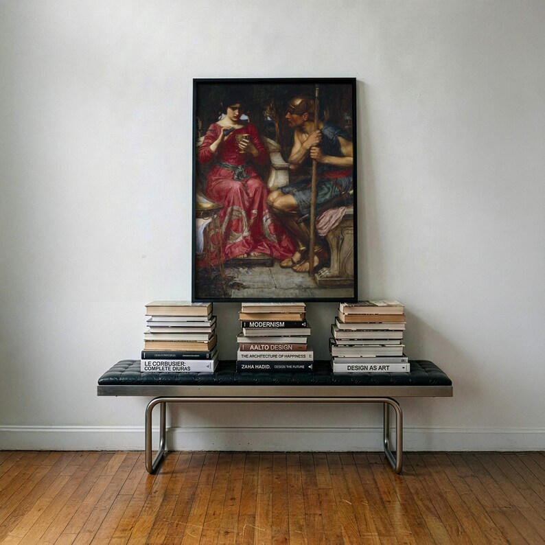 May include: A rectangular framed painting depicting a woman in a red dress and a man in armor holding a spear, positioned above a black leather bench with metal legs. Three stacks of books are arranged on the bench beneath the artwork.