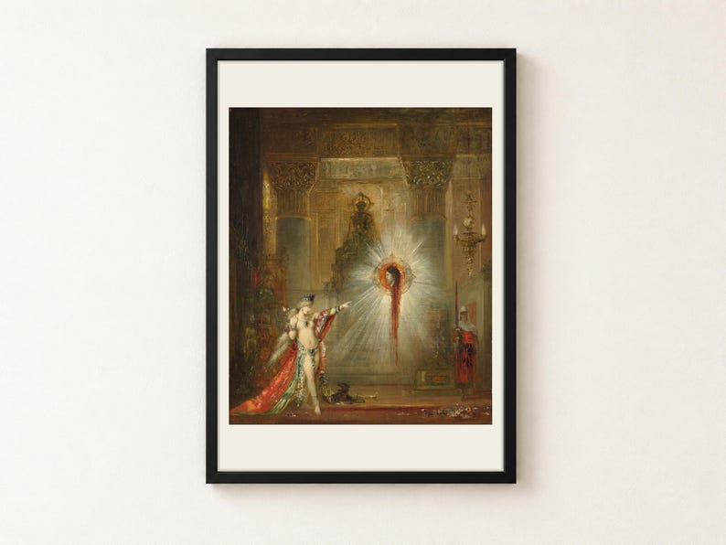 The Apparition by Gustave Moreau, 1876 to 1877, as a framed print in a black frame on a cream wall. In a gilded palace, a crowned woman in jewels and a red embroidered robe points at the severed head of John the Baptist floating in a burst of white light, a guard with a halberd standing at right, shown with a warm off-white border.