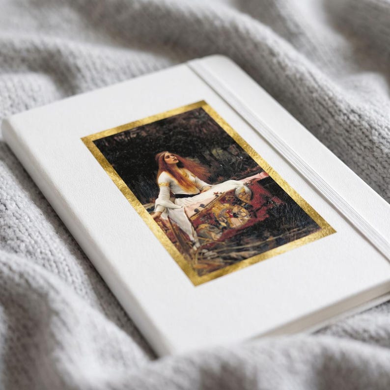 May include: A white hardcover notebook featuring a rectangular print of a painting depicting a person with long red hair in a white dress, framed by a metallic gold border. The notebook has a white elastic closure band attached to the cover.