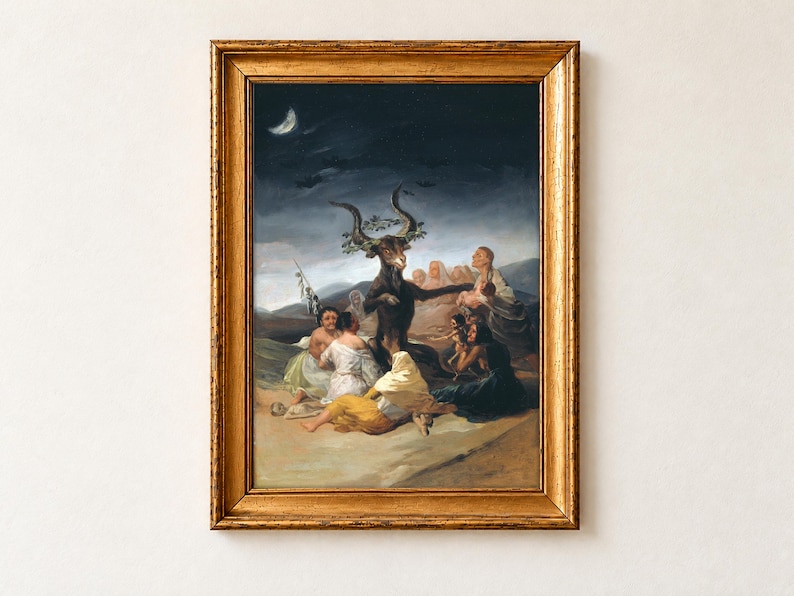 Witches' Sabbath by Francisco Goya, 1798, as a framed print in an antique gold frame on a cream wall. A great horned goat crowned with oak leaves sits among a circle of witches who offer it children, beneath a crescent moon and flying bats.