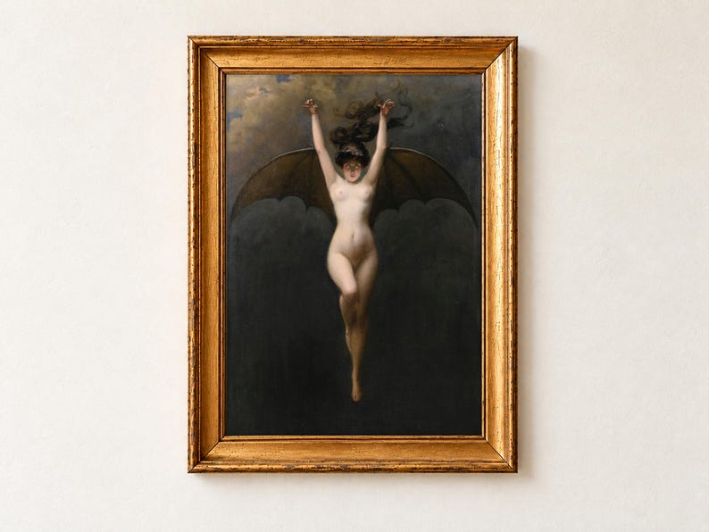 The Bat Woman by Albert Joseph Penot, about 1890, as a framed print in an antique gold frame on a cream wall. A pale woman with great dark bat wings hangs with her arms raised above her head against a smoky night sky.