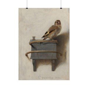 May include: An oil painting of a goldfinch perched on a grey wooden box with a curved metal perch. The bird has brown, white, and yellow feathers. A thin chain is attached to the box. The text C FABRITIVS 1654 is visible at the bottom.