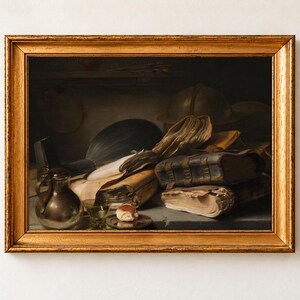 Still Life with Books by Jan Lievens, about 1628 to 1632, as a framed print in an antique gold frame on a cream wall. A heap of worn leather books and loose papers lies beside a lute, a globe, a pewter jug and a glass on a dim table.