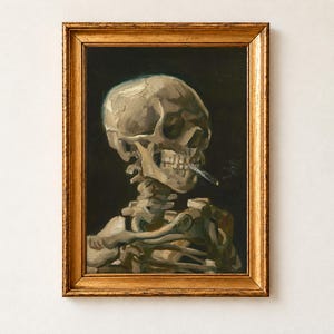 Head of a Skeleton with a Burning Cigarette by Vincent van Gogh, 1886, as a framed print in an antique gold frame on a cream wall. A skull and upper spine of a skeleton, a lit cigarette clamped between its teeth, against a dark background.
