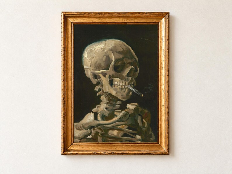 Head of a Skeleton with a Burning Cigarette by Vincent van Gogh, 1886, as a framed print in an antique gold frame on a cream wall. A skull and upper spine of a skeleton, a lit cigarette clamped between its teeth, against a dark background.