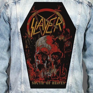 May include: A light blue denim jacket featuring a large, coffin-shaped back patch. The patch displays a red and black graphic of a skull with the text SLAYER in yellow at the top and SOUTH OF HEAVEN in yellow at the bottom, centered on the back.