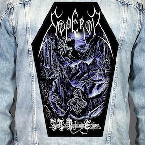May include: A light blue denim jacket featuring a large, coffin-shaped back patch. The patch displays a dark, purple-toned mountain landscape with the text "EMPEROR" at the top and "In The Nightside Eclipse" printed in white at the bottom.