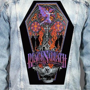May include: A light blue denim jacket featuring a large, coffin-shaped back patch. The patch displays a purple winged figure, orange flames, and stained glass motifs. The text reads Black Sabbath, Chicago Illinois, United Center, and 2016.