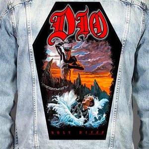 May include: A light blue denim jacket featuring a large, coffin-shaped back patch. The patch displays the red text DIO above an illustration of a horned figure and a person in water, with the red text HOLY DIVER at the bottom of the black background.