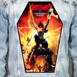 May include: A light blue denim jacket featuring a large, coffin-shaped back patch with the Manowar The Triumph of Steel album artwork. The graphic depicts a warrior holding a sword and hammer amidst red flames, lightning, and various figures.
