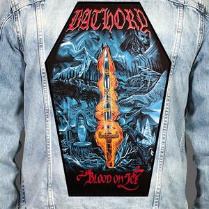 May include: A light blue denim jacket featuring a large, coffin-shaped back patch. The patch displays a flaming sword, a horse, a snake, and a figure, with the text BATHORY at the top and BLOOD ON ICE at the bottom in a stylized red font.