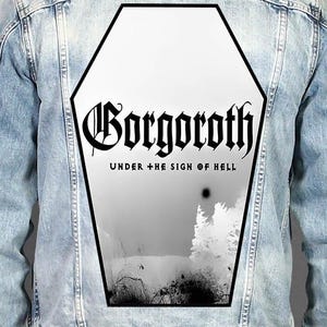 Könnte beinhalten: Eine hellblaue Jeansjacke mit einem großen, sargförmigen Aufnäher auf dem Rücken. Der Aufnäher zeigt eine schwarz-weiße Landschaft mit dem Text Gorgoroth und Under The Sign Of Hell in gotischer Schrift innerhalb der schwarz umrandeten Form.