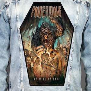 May include: A light blue denim jacket featuring a large, coffin-shaped back patch. The patch displays a dark, detailed illustration of a werewolf crushing a globe, with the text "POWERWOLF" at the top and "MY WILL BE DONE" at the bottom.