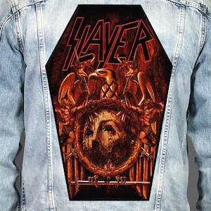 May include: A light blue denim jacket featuring a large, coffin-shaped back patch. The patch displays the red Slayer logo above a dark, detailed illustration of an eagle, a central face, and swords in shades of deep red, orange, and black.