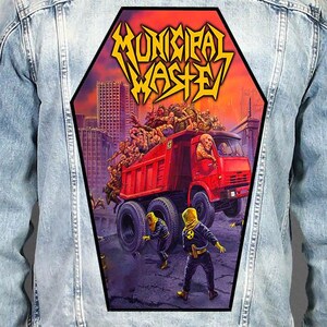 May include: A light blue denim jacket featuring a large, coffin-shaped back patch. The patch displays a red dump truck filled with zombies in a city, with the yellow text MUNICIPAL WASTE at the top and figures in yellow hazmat suits below.